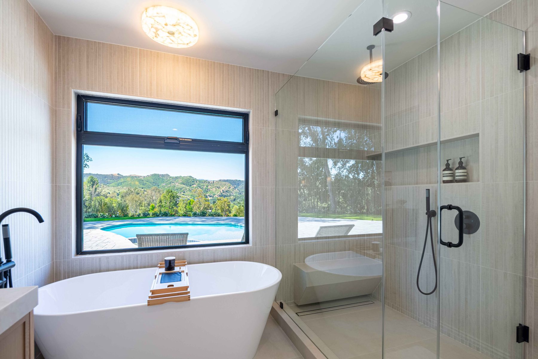 Wet room with freestanding tub and pool view
